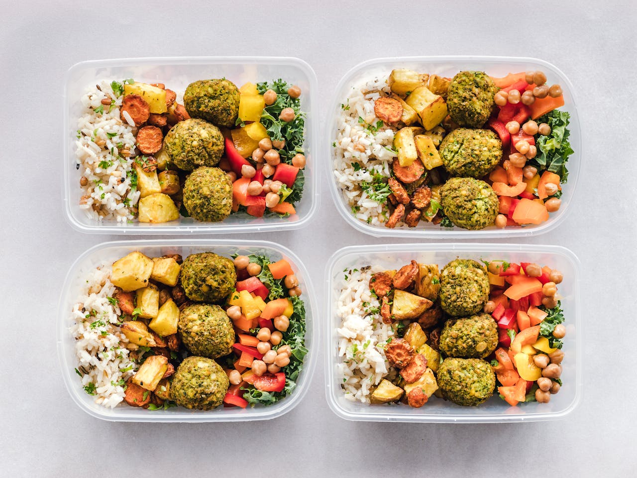 about-01 Colorful meal prep containers with falafel, chickpeas, rice, and vegetables for a healthy lifestyle.