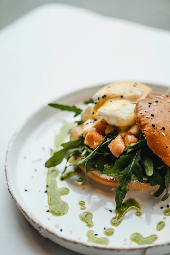 Delicious gourmet salmon burger topped with arugula and hollandaise sauce on a rustic plate.